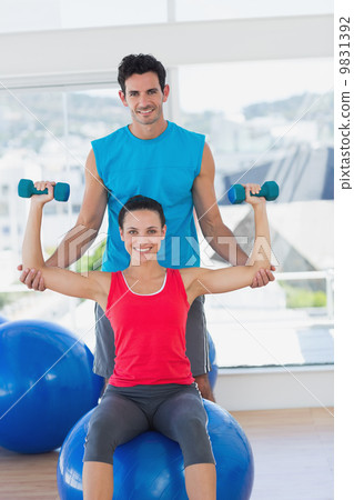 Male trainer helping woman with her exercises at gym 9831392