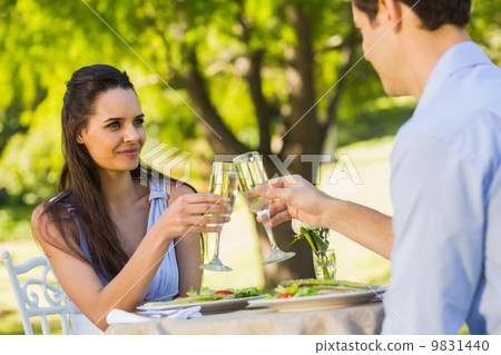 Couple toasting champagne flutes at an outdoor cafÃ© 9831440