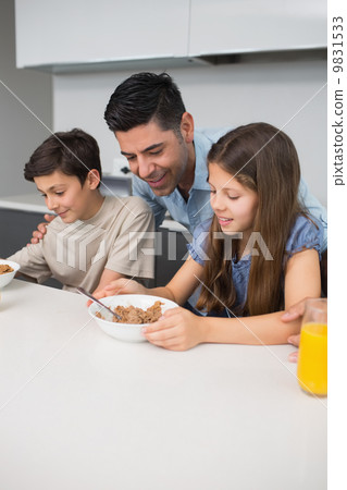 Young kids enjoying breakfast with father in kitchen 9831533