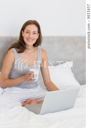 Relaxed young woman using laptop in bed 9831657