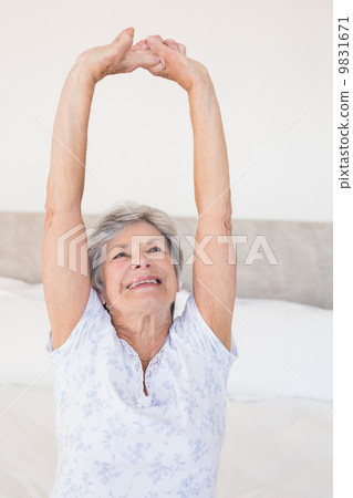 Senior woman stretching on bed 9831671