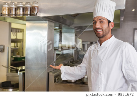 Smiling young chef looking at camera showing his workplace 9831672