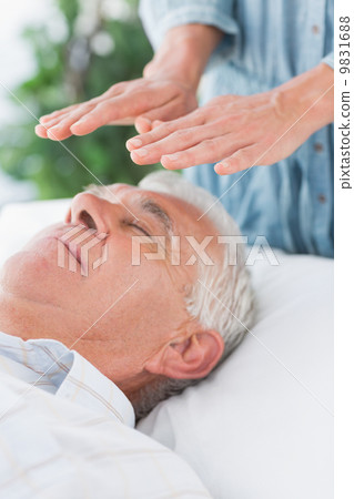 Senior man having Reiki treatment Senior man having Reiki treatment 9831688