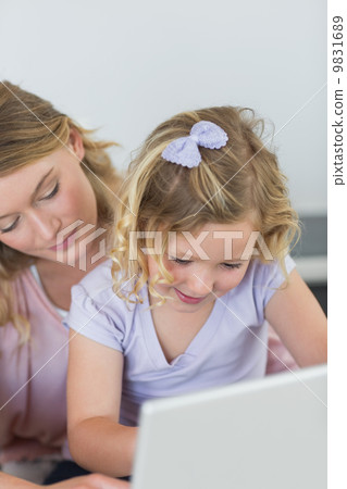 Girl using laptop with mother 9831689
