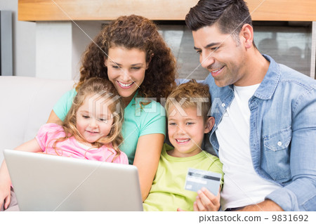 Happy family sitting on sofa using laptop together to shop onlin Happy family sitting on sofa using laptop together to shop onlin 9831692