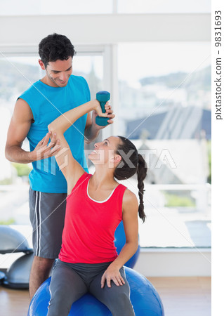 Male trainer helping woman with her exercises at gym Male trainer helping woman with her exercises at gym 9831693
