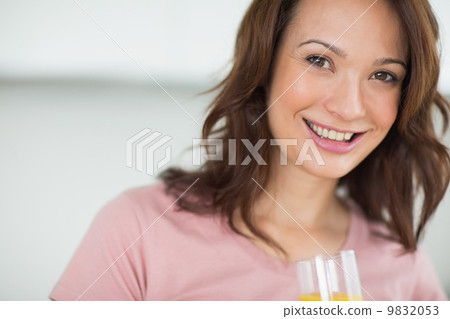 Closeup of a smiling woman holding orange juice Closeup of a smiling woman holding orange juice 9832053