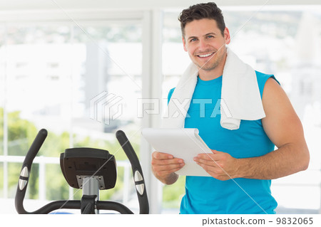 Smiling trainer with clipboard in gym 9832065