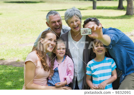 Man taking picture of extended family at park Man taking picture of extended family at park 9832091