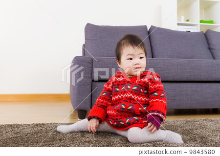 Baby girl seating on carpet at home 9843580