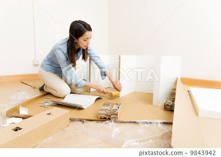 Asian woman using hammer for assembling furniture 9843942