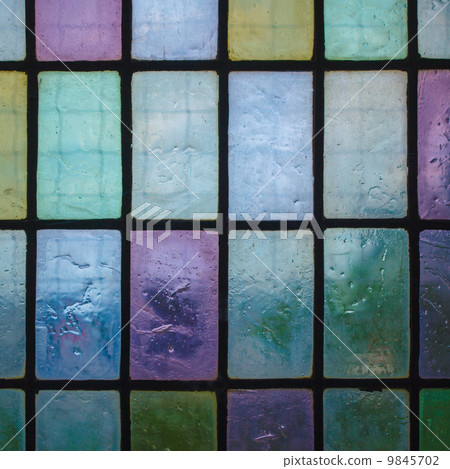 colored stained glass window with regular block pattern blue green tone 9845702