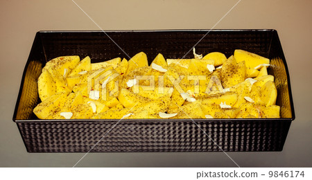 Raw peeled potatoes with spices and butter in tray. Food. 9846174