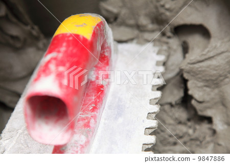 Construction worker is tiling at home tile floor adhesive 9847886