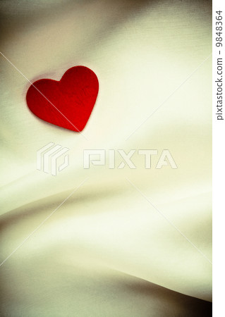 Red wooden decorative heart on white silk background. 9848364