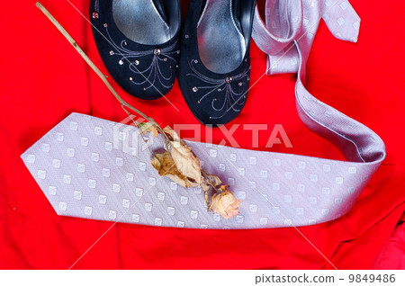 Black female shoes, rose and necktie on red background 9849486