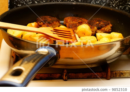 Seasoned potato slices in skillet pan in kitchen Seasoned potato slices in skillet pan in kitchen 9852310