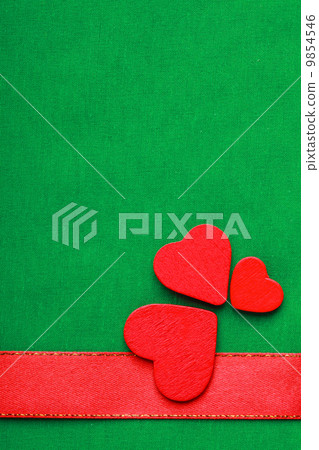 Red wooden decorative hearts on green cloth background 9854546