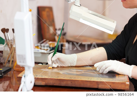 Artist applies lacker on the icon 9856164