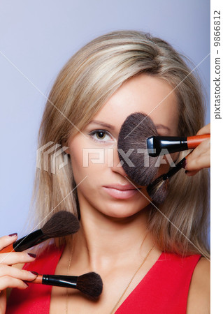 Beauty procedures, woman holds make-up brushes near face. Beauty procedures, woman holds make-up brushes near face. 9866812