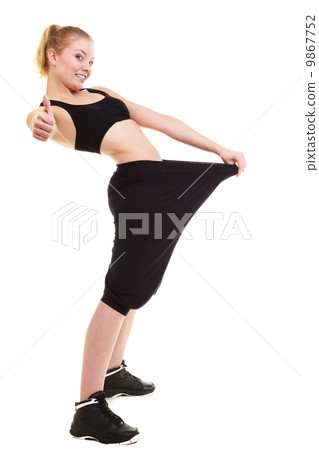 happy woman showing how much weight she lost, big pants 9867752