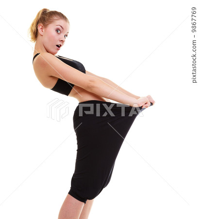happy woman showing how much weight she lost, big pants 9867769