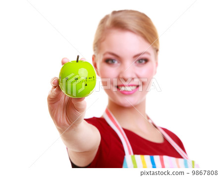 Happy housewife or chef in kitchen apron showing apple timer Happy housewife or chef in kitchen apron showing apple timer 9867808