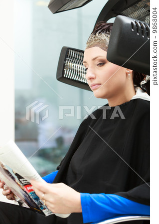 Haidressing salon. Woman dying hair reading magazine. Modern equipment. Haidressing salon. Woman dying hair reading magazine. Modern equipment. 9868004