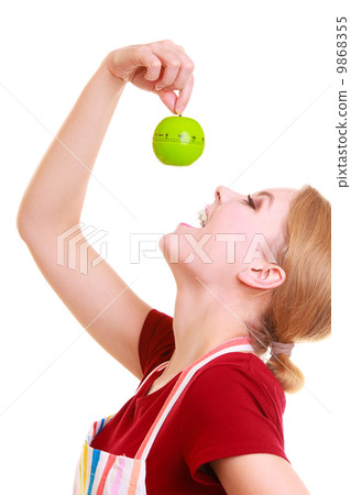 Funny housewife in kitchen apron trying to eat apple timer isolated 9868355