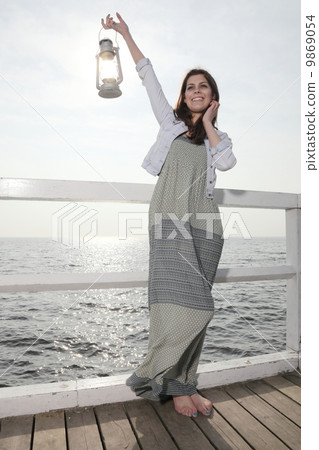 Girl on pier with kerosene lamp 9869054