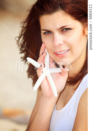 young woman on seacoast with shell in hand young woman on seacoast with shell in hand 9869311