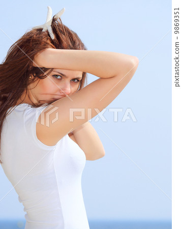 young woman on seacoast with shell in hand 9869351