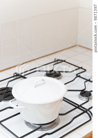 A white pot placed in a gas cooktop 9871397