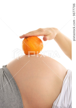Pregnant woman's abdomen with orange 9877786