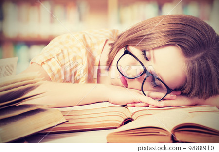 tired student girl with glasses sleeping on books in library 9888910