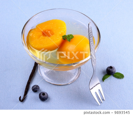 Peach compote in glass bowl with blueberries and vanilla 9893545