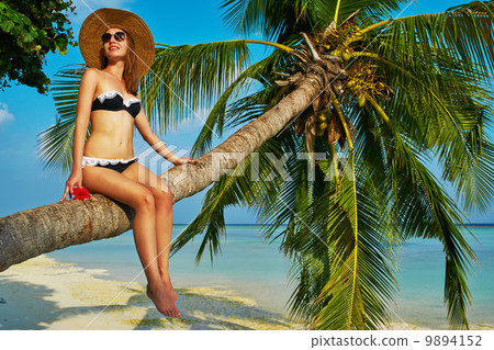 Woman sitting on a palm tree at tropical beach Woman sitting on a palm tree at tropical beach 9894152