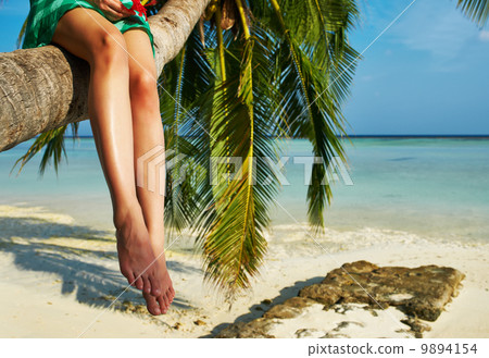 Woman sitting on a palm tree at tropical beach Woman sitting on a palm tree at tropical beach 9894154