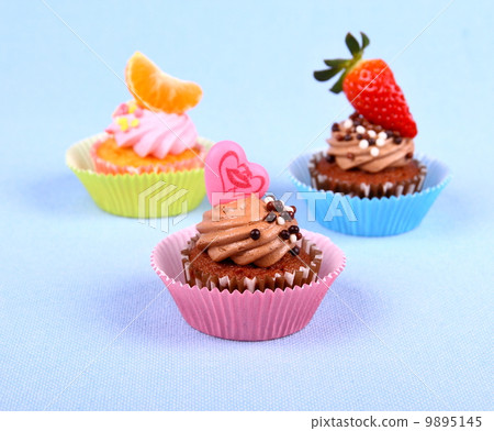 Three appetizing cupcakes with heart, tangerine, and strawberry Three appetizing cupcakes with heart, tangerine, and strawberry 9895145