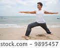 Asian male practising yoga on the beach 9895457