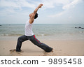 Asian male practising yoga on the beach 9895458