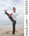 Asian male practising yoga on the beach 9895459