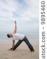 Asian male practising yoga on the beach 9895460