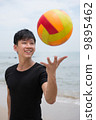 Asian young good looking man playing with a colourful ball on the beach 9895462
