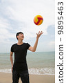 Asian young good looking man playing with a colourful ball on the beach 9895463