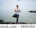 Asian male doing yoga on the beach 9895469