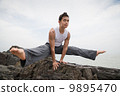 Asian male doing yoga on the beach 9895470