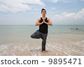 Asian male doing yoga on the beach 9895471