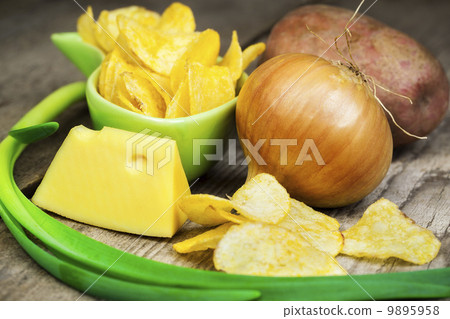 Crispy chips in green bowl on wooden boards 9895958