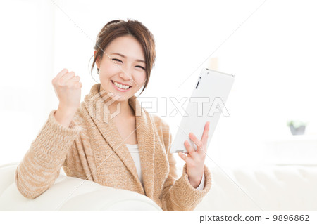 A woman watching a tablet in a room A woman watching a tablet in a room 9896862
